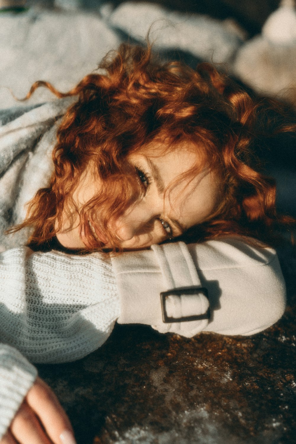 a woman with red hair laying on a rock