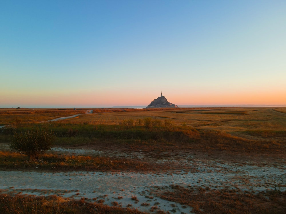 a grassy field with a small tower in the distance