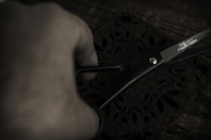 Hands carefully cutting fabric patterns on a large table.