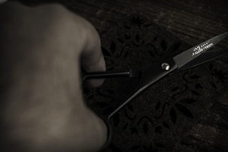 Close-up of hands carefully cutting premium fabric with precision tools in a modern workshop.