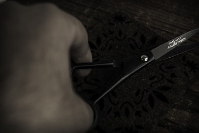 Close-up of hands cutting fabric with scissors on a tailor’s table.