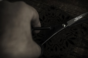 Close-up of a tailor’s hands carefully cutting premium fabric with precision scissors.