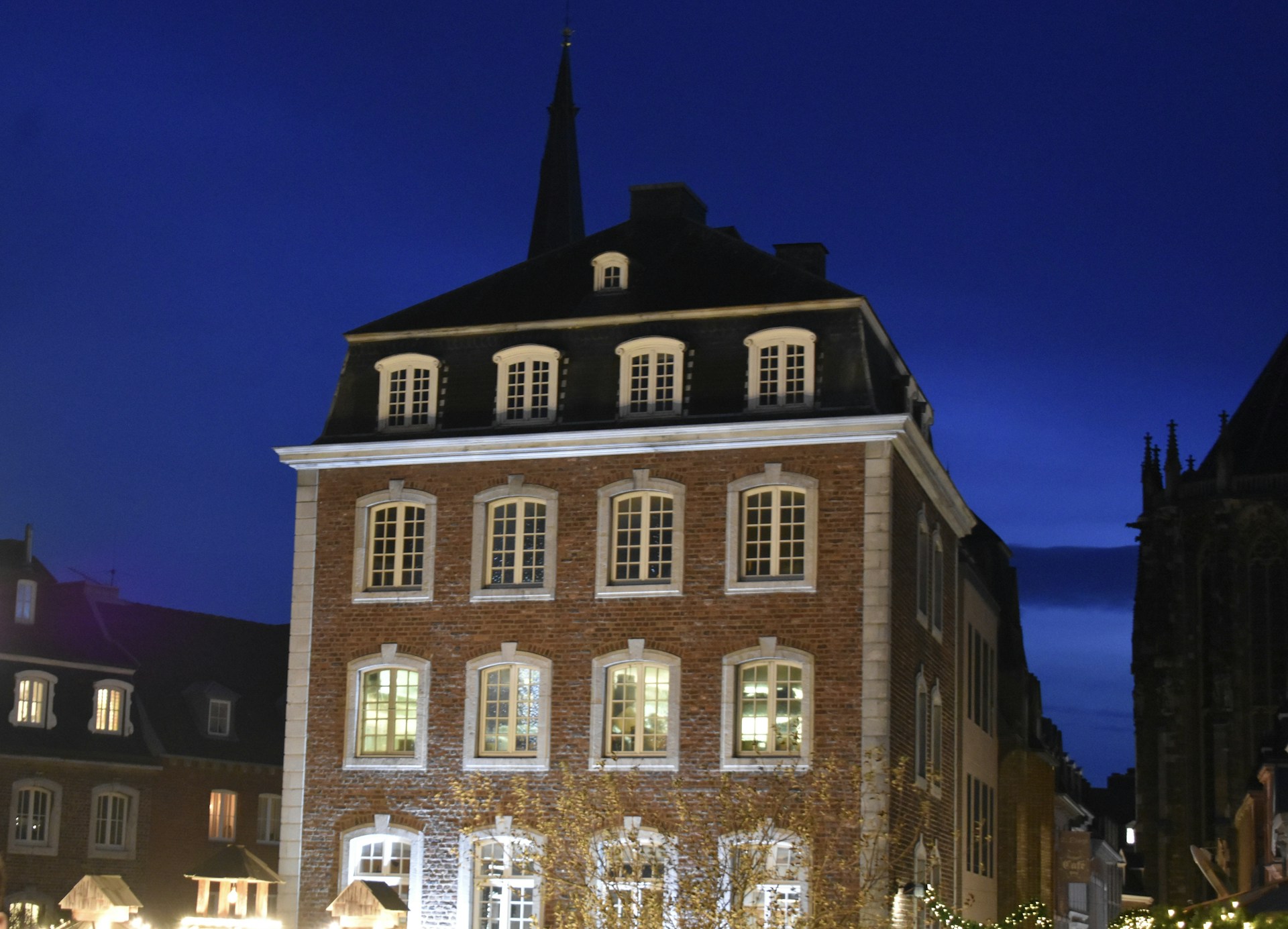 An evening shot of the brownstone arts studio glowing warmly, with artworks displayed in the windows reflecting community spirit.
