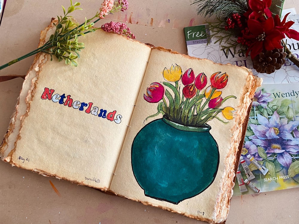 an open book with flowers in a vase on top of it