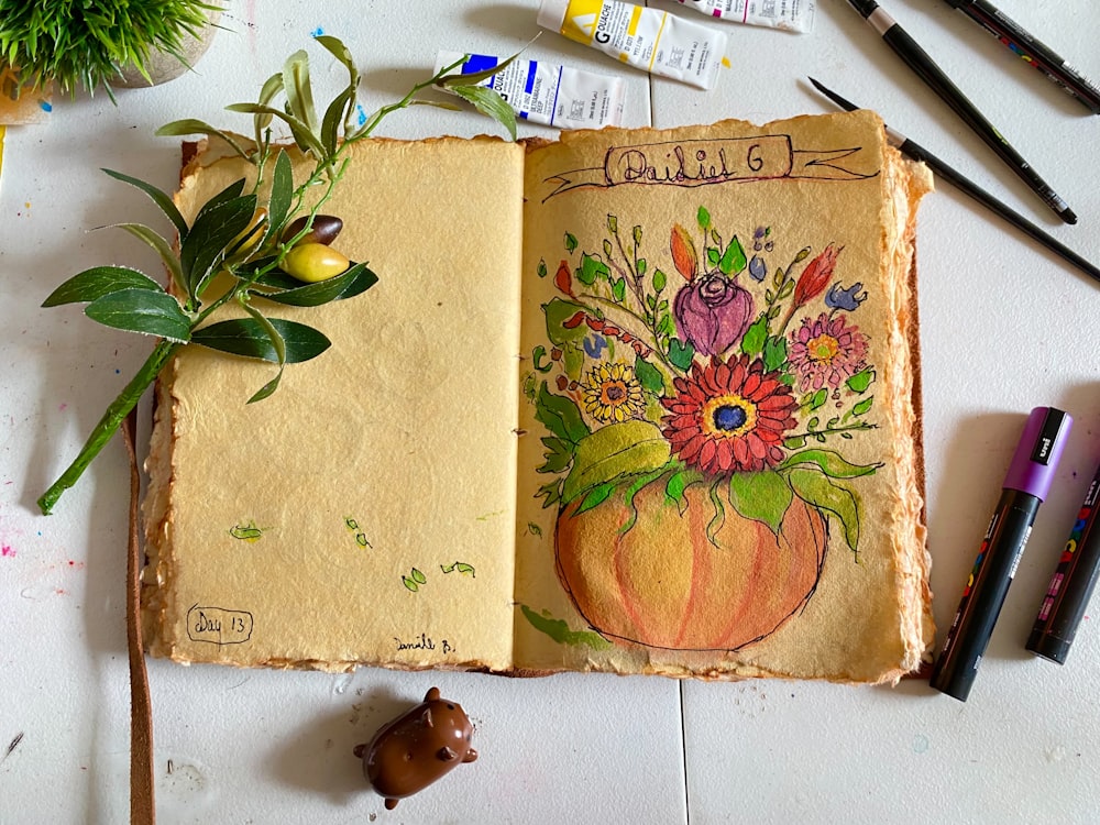 an open book with a flower arrangement on top of it