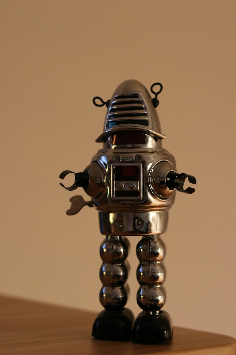 a silver robot toy sitting on top of a wooden table