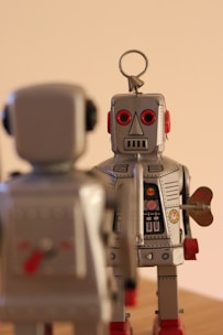 a couple of toy robots standing on top of a wooden table