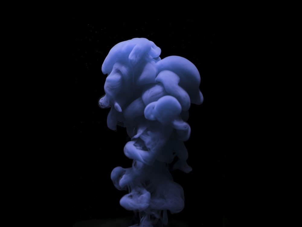 a blue substance floating in the air on a black background