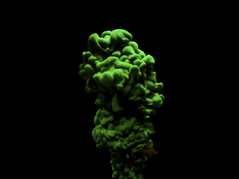 a green substance floating in the air on a black background