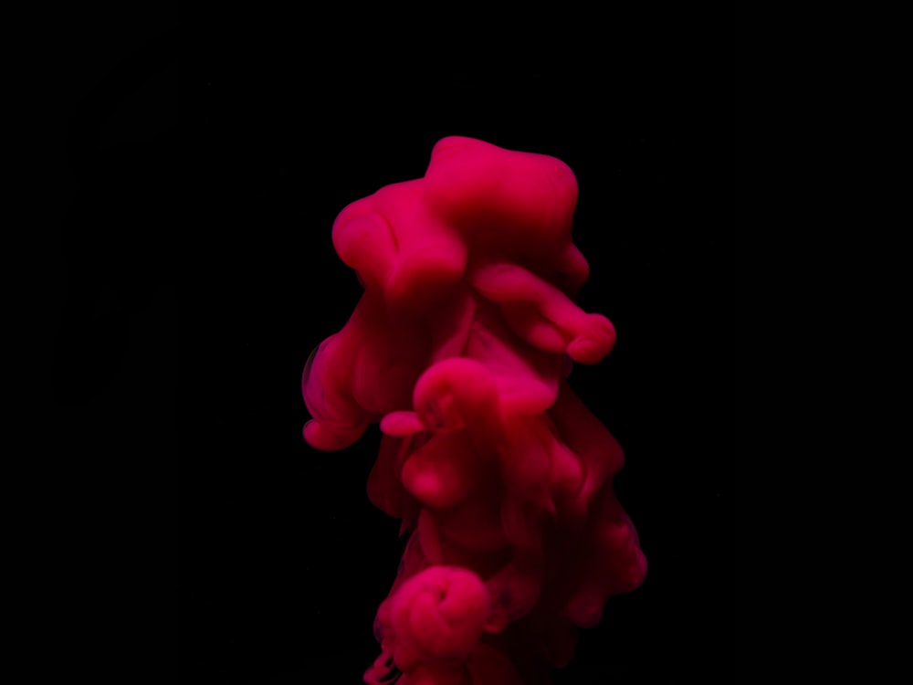 a red substance floating in the air on a black background