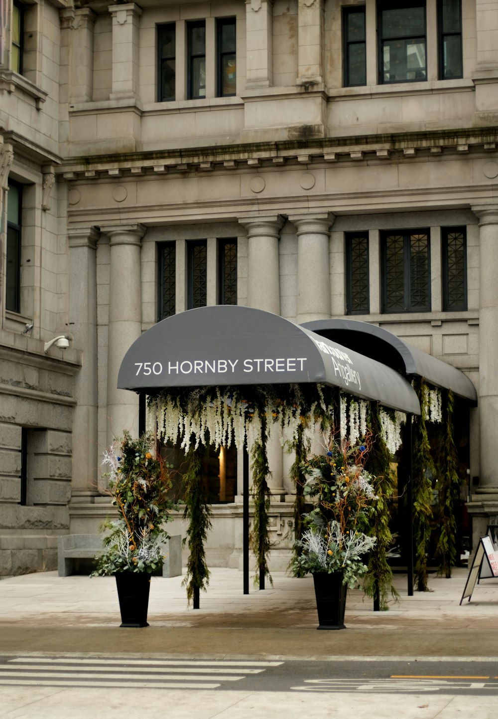 a bus stop covered in flowers and greenery in front of a building