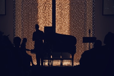 a man sitting in front of a piano in a dark room