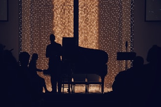 a man sitting in front of a piano in a dark room