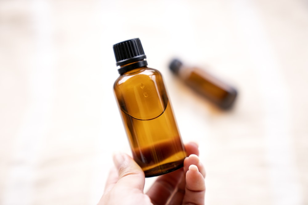 a person holding a bottle of essential oils