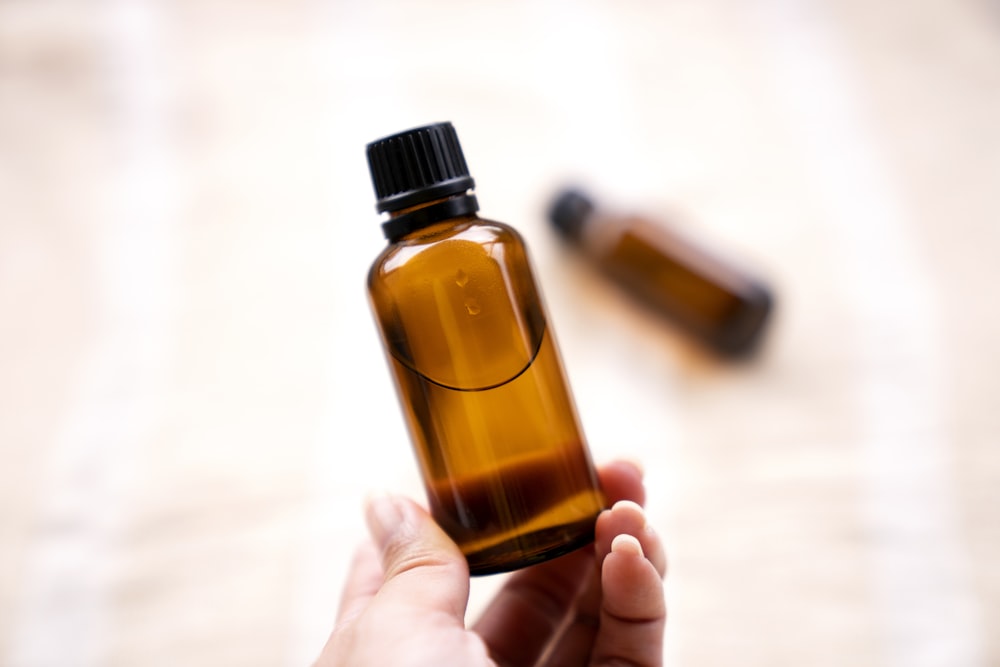 a person holding a bottle of essential oils