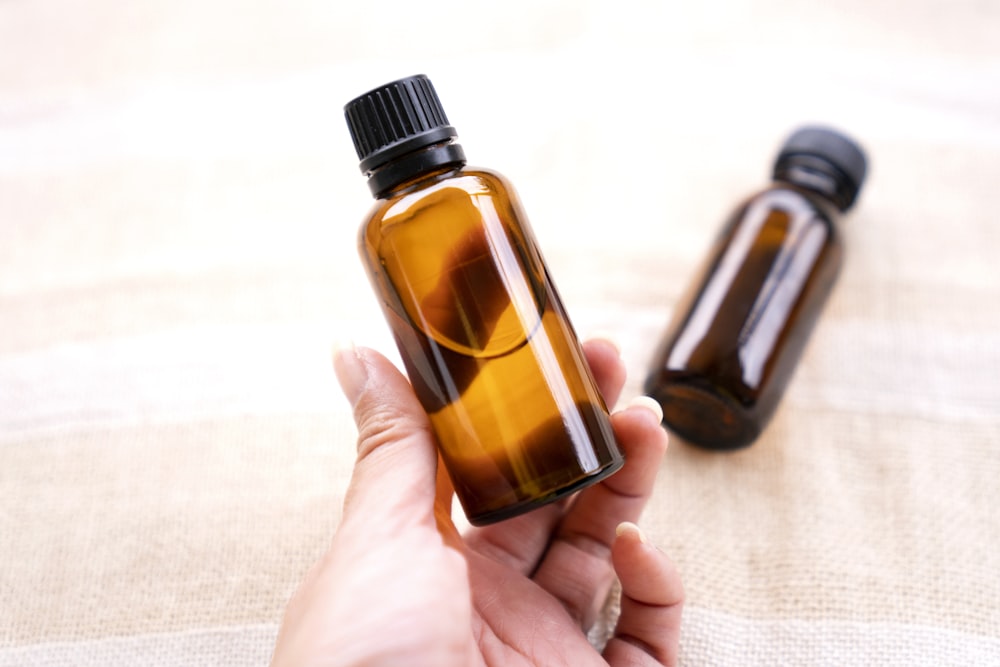 a person holding a bottle of essential oils