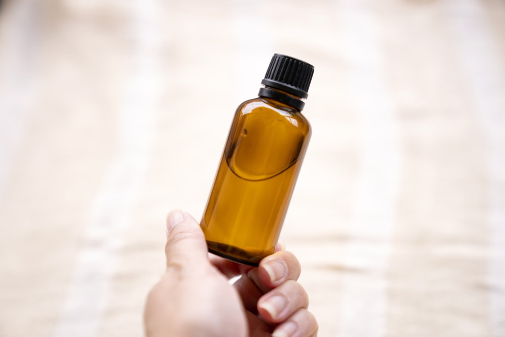a person holding a bottle of essential oils