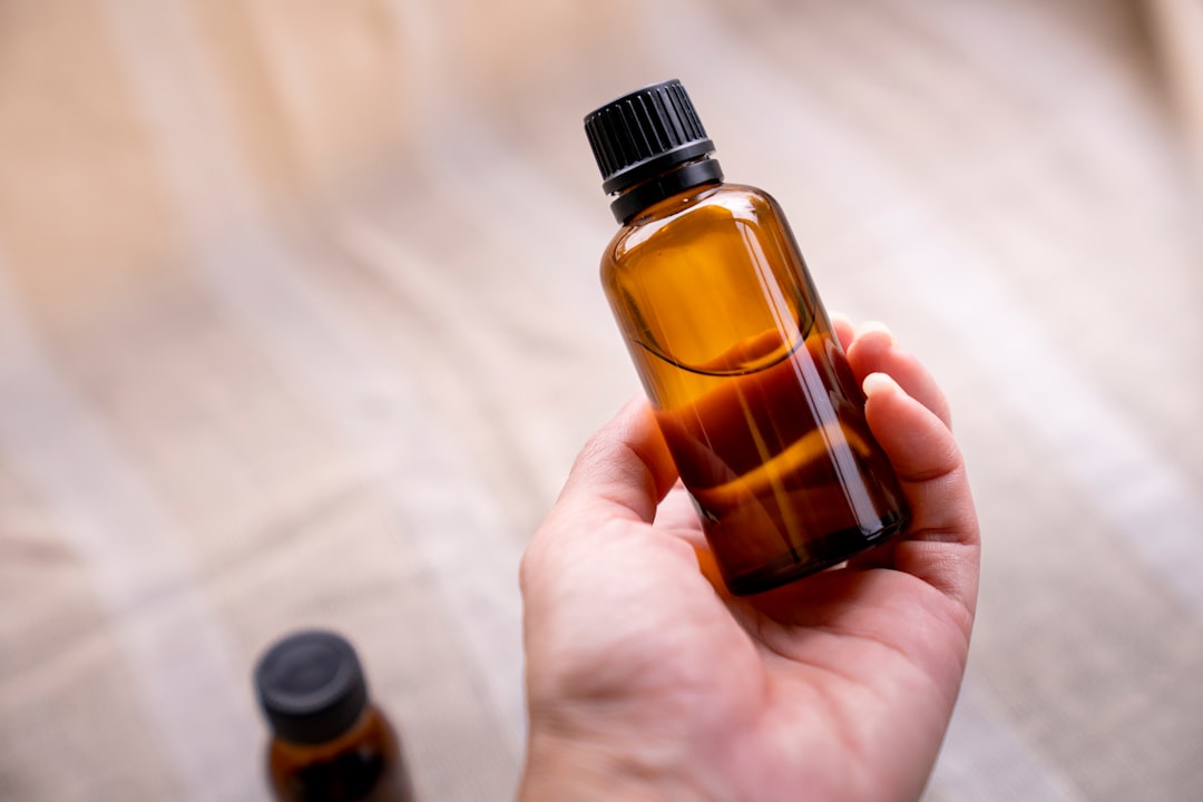 a person holding a bottle of essential oils, Hand holding amber glass bottle