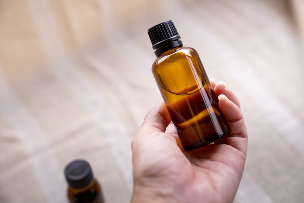 a person holding a bottle of essential oils