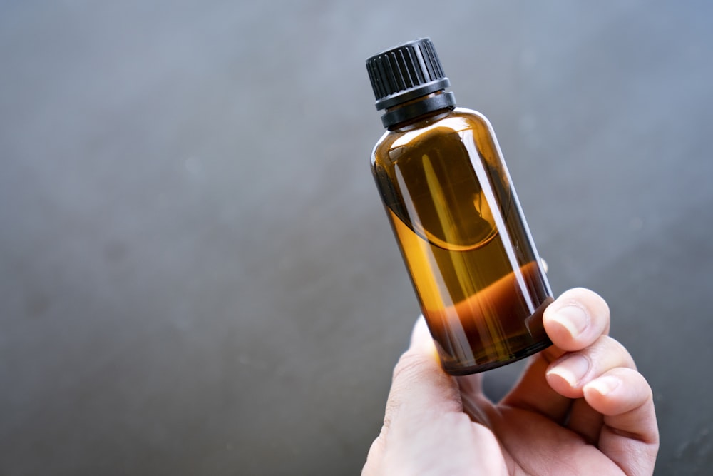 a person holding a bottle of essential oils