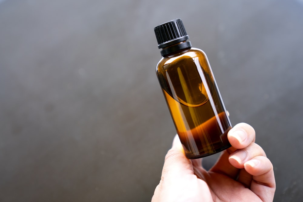 a person holding a bottle of essential oils