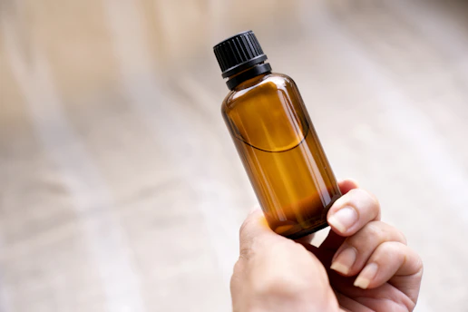 Close-up of a Melara Max bottle with natural ingredients softly blurred in the background.