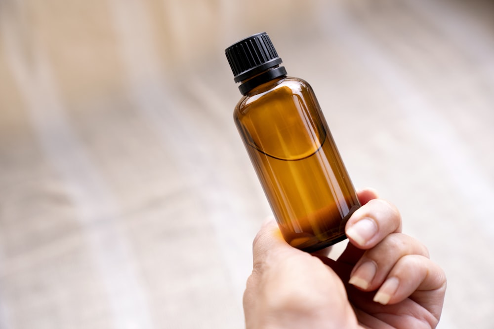 a person holding a bottle of essential oils