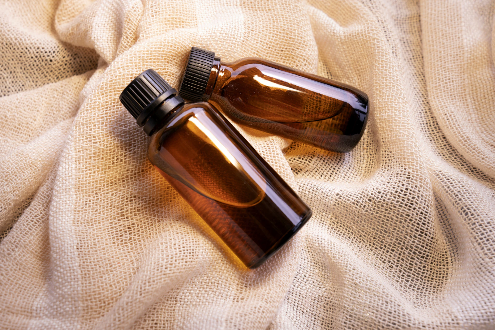 Amber glass bottles of medicated oil resting on folded cloth