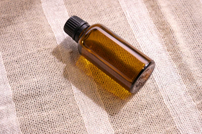Obsidian glass bottle resting on antique gold fabric with soft shadows.