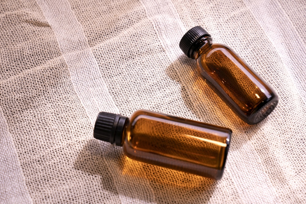 Dos pequeñas botellas marrones sentadas encima de una mesa