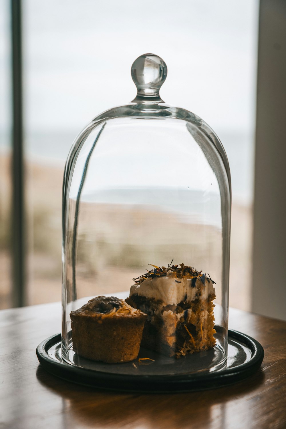 um bolo sob uma cúpula de vidro em uma mesa de madeira