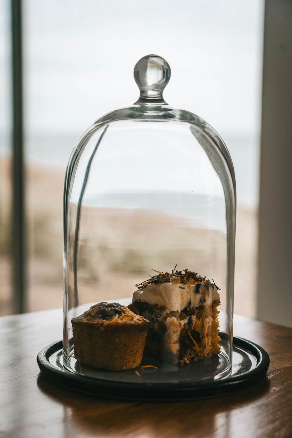 a cake under a glass dome on a wooden table