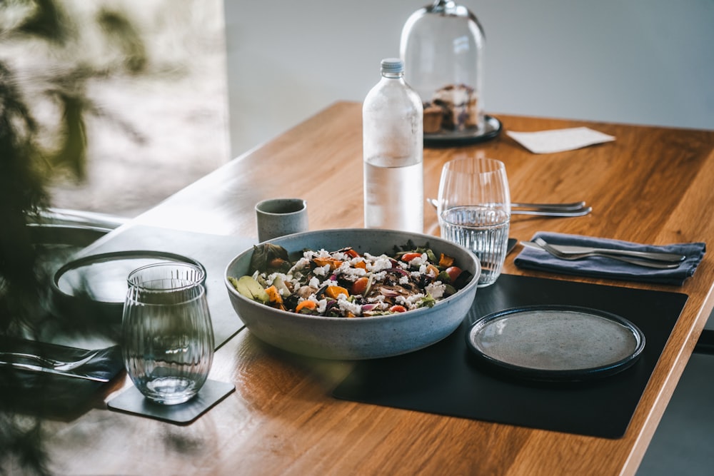 a wooden table topped with a bowl of food