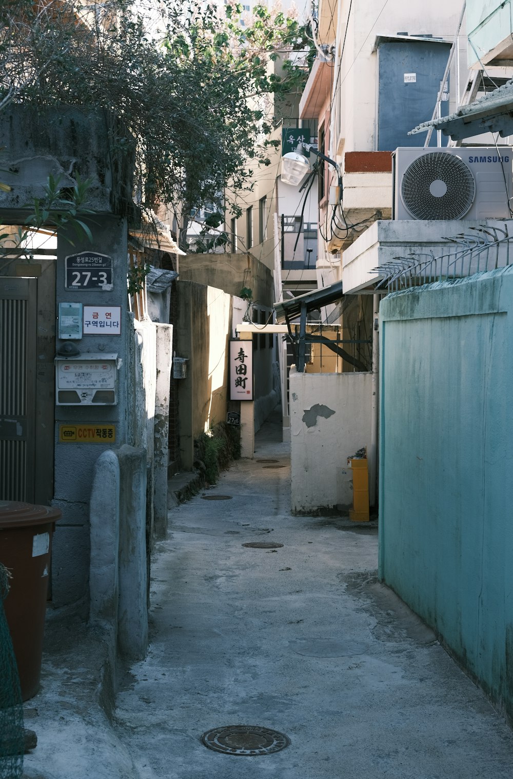 a narrow alley way with a fan on the wall