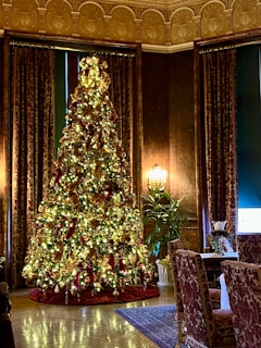 Upscale luxury Christmas tree decorated with sparkling ornaments and elegant ribbons in a stylish living room.