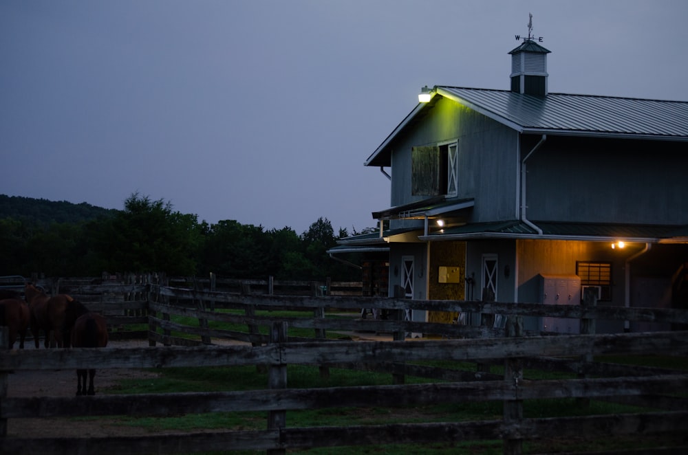 a barn at night with horses grazing in the foreground