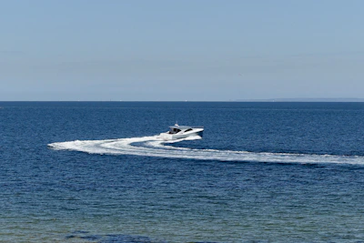Premium speedboat cutting through the waves under a clear blue sky.