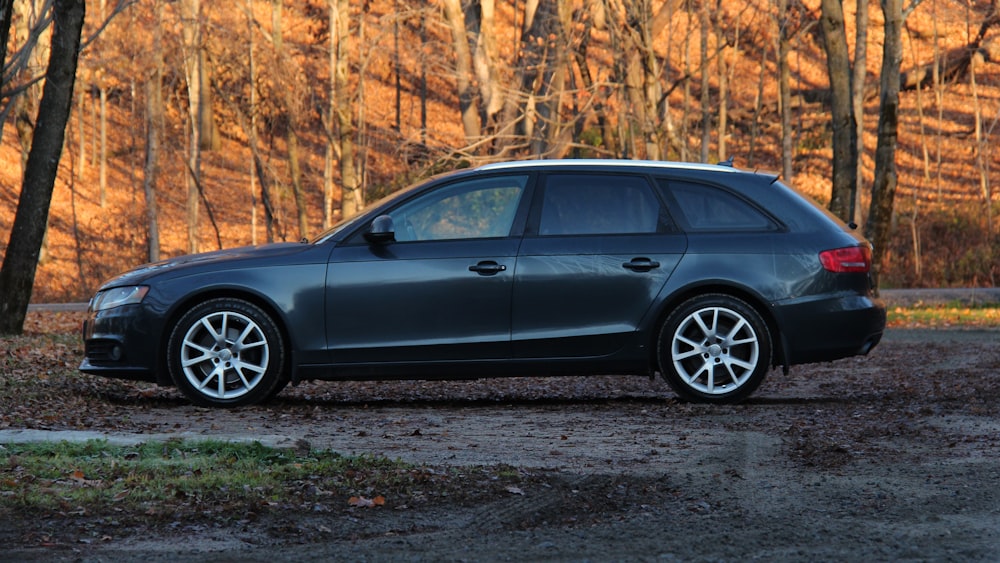 a black car parked in front of a wooded area