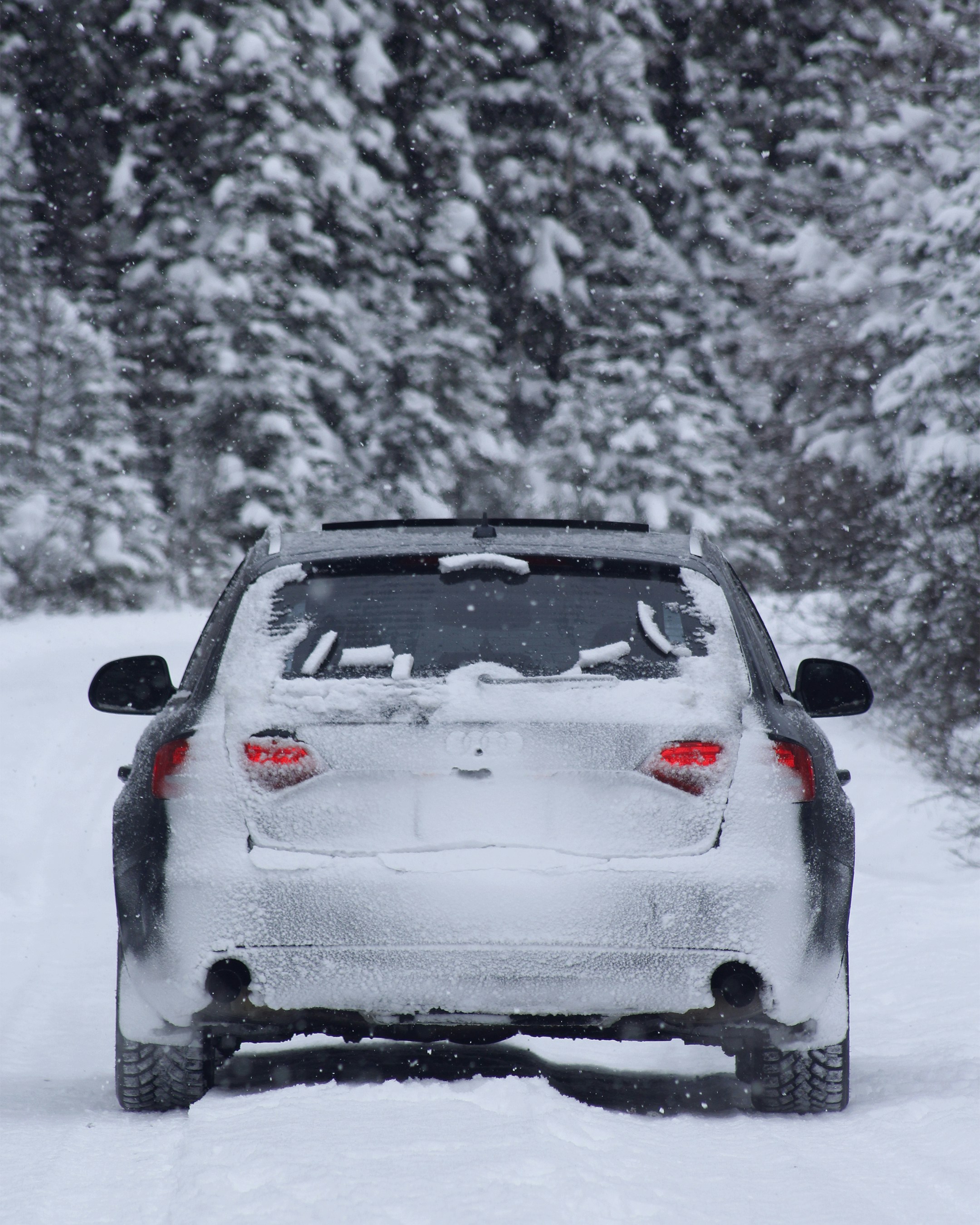 a white car driving down a snow covered road