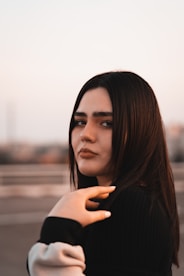 a woman with long brown hair wearing a black sweater