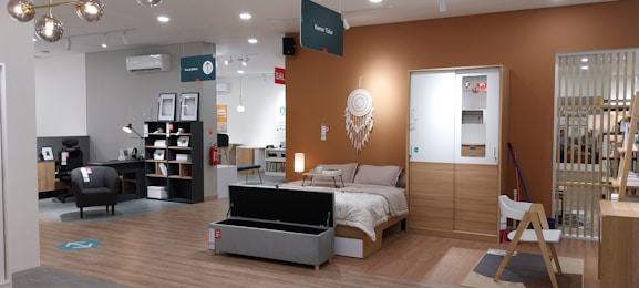 a room with a bed, desk, chair and shelves
