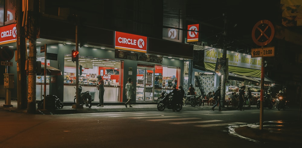 a group of people riding motorcycles down a street at night