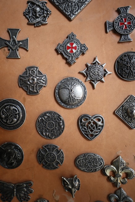 A set of custom metal badges laid out on a rustic wooden table, showcasing precision laser work.