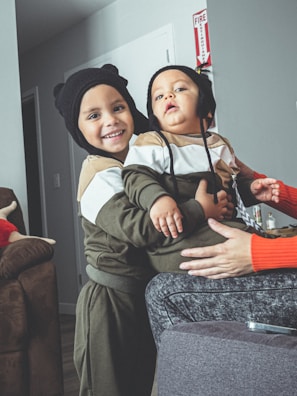 A playful scene of siblings wearing matching green and cream outfits, laughing together in a cozy room.