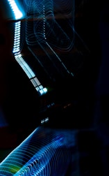 Abstract light patterns created with long exposure photography, featuring swirling lines and glowing spots in a dark setting.