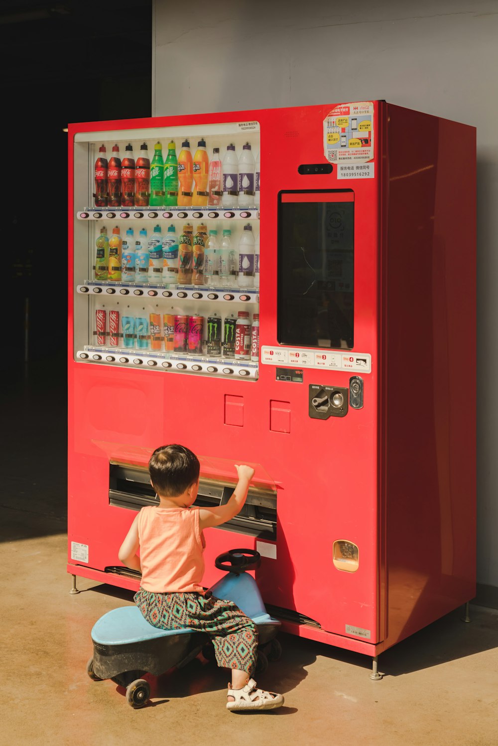 a little boy playing with a vending machine