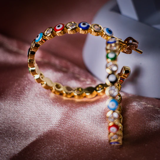 Close-up of a pair of blue gold feather earrings with semi-precious stones shimmering softly.