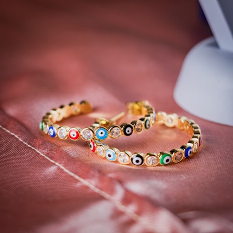 A pair of cartouche earrings showcased with traditional Egyptian motifs in the background.