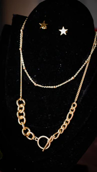 Stylish layered gold necklaces arranged on a black velvet surface
