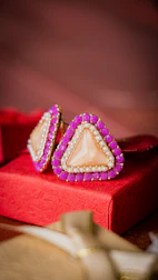 a pair of pink and white earrings sitting on top of a red box